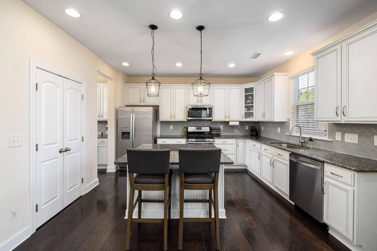 Two upholstered counter stools at a kitchen island under two lantern pendants
