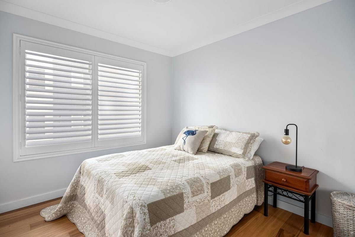 A quilted patchwork bedspread long enough to reach the floor at the side and the foot of the bed
