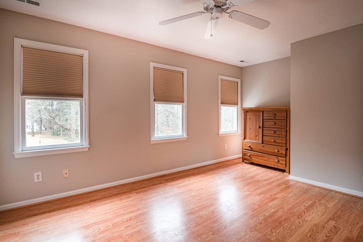 Three windows, each with a beige pleated shade mounted inside the frame and lowered over the upper glass