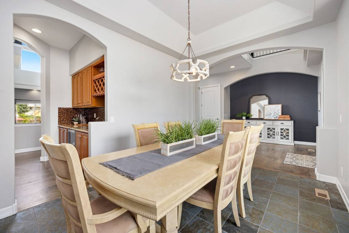A gray runner down a long table with two low planters of grass, and a white sideboard with a framed print behind