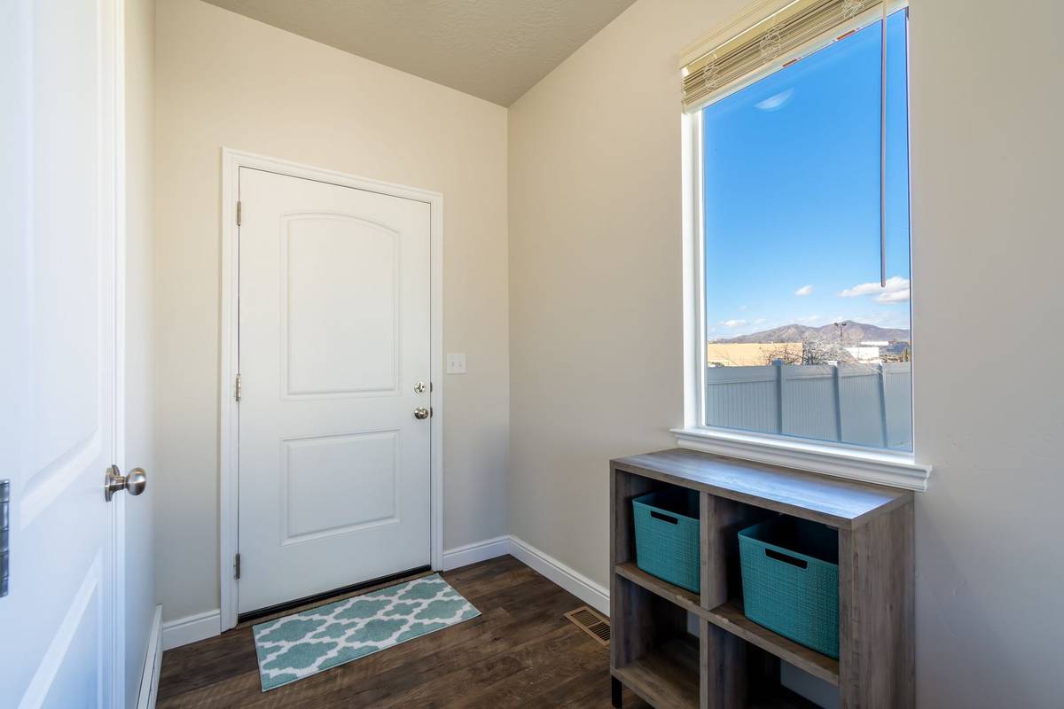 A small patterned rug just inside a white front door, with a low cubby shelf of baskets under the window