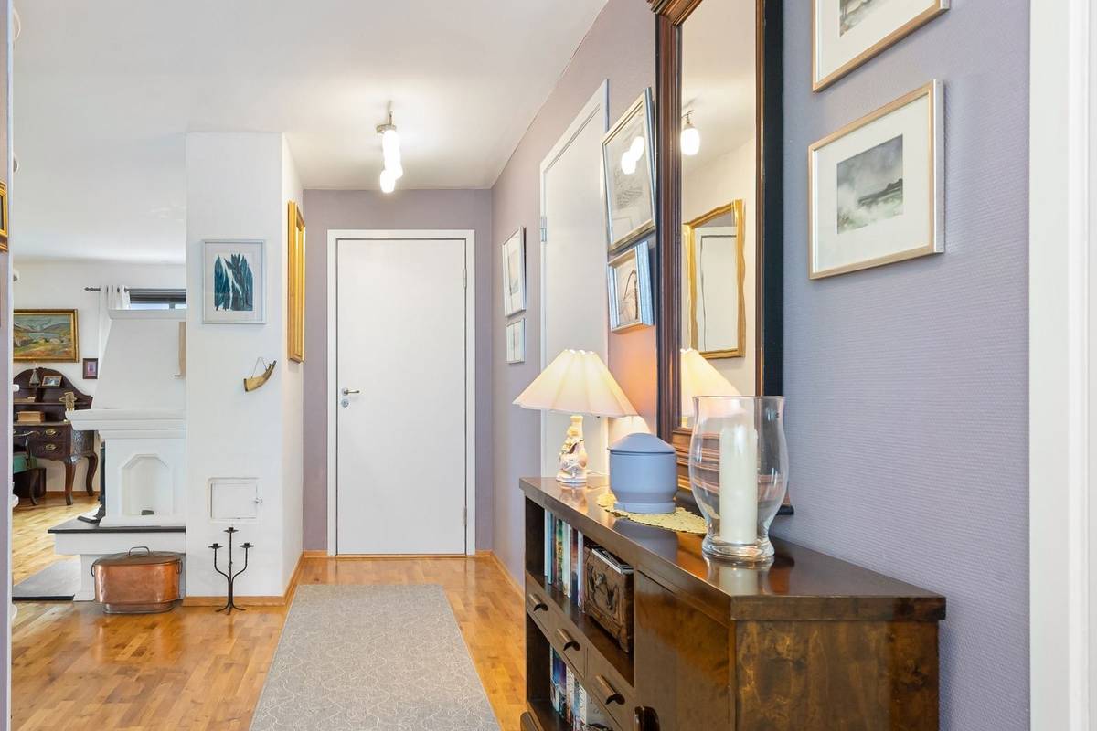Small framed prints hung along a lavender hallway above a wood console, with a tall mirror and a runner rug