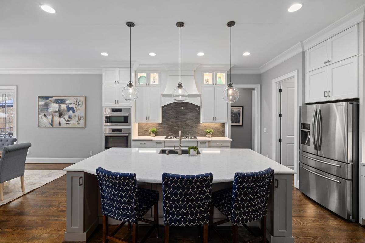 Three glass globe pendants spaced evenly over a large kitchen island with three counter stools