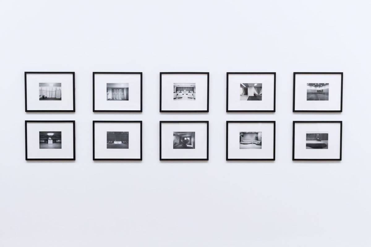 Ten black frames hung in two even rows on a white wall